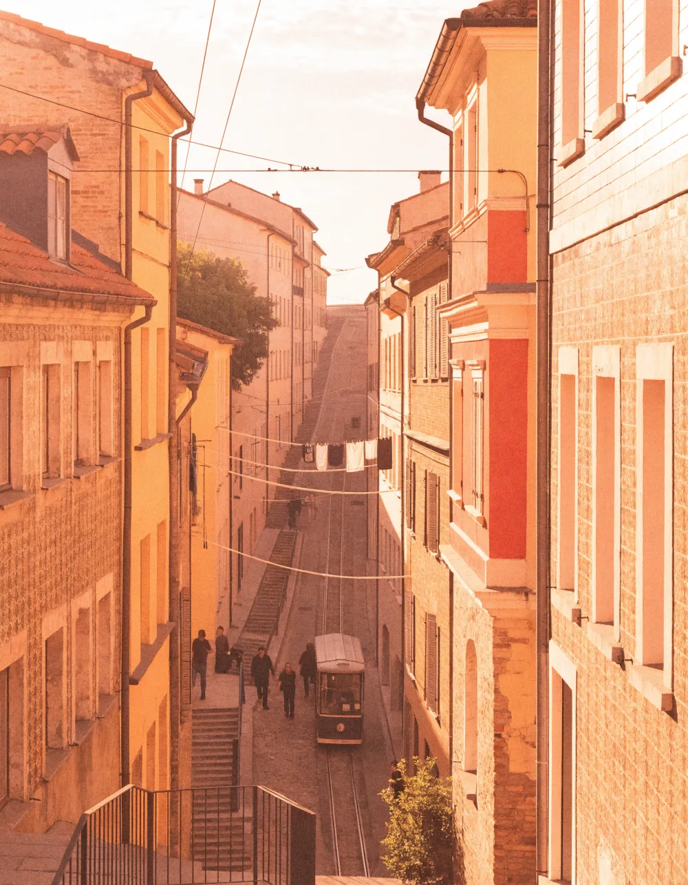 A vintage tram climbing a steep street of tiled facades in warm afternoon light