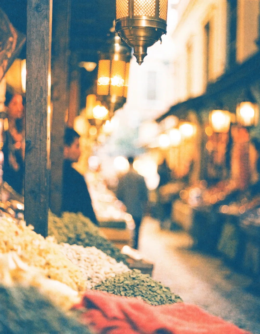 Brass lanterns glowing over a spice-market alley at dusk